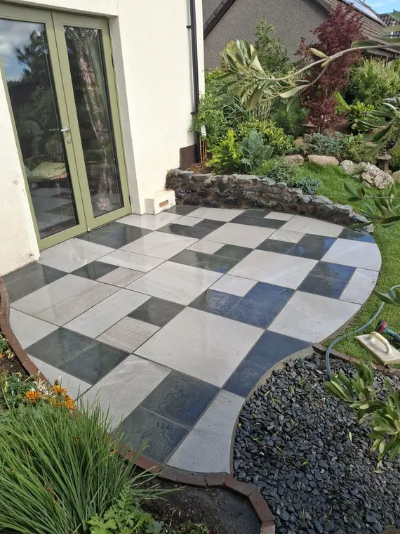 Black and white paving framed by a slate margin and planting, tying the patio into the garden.