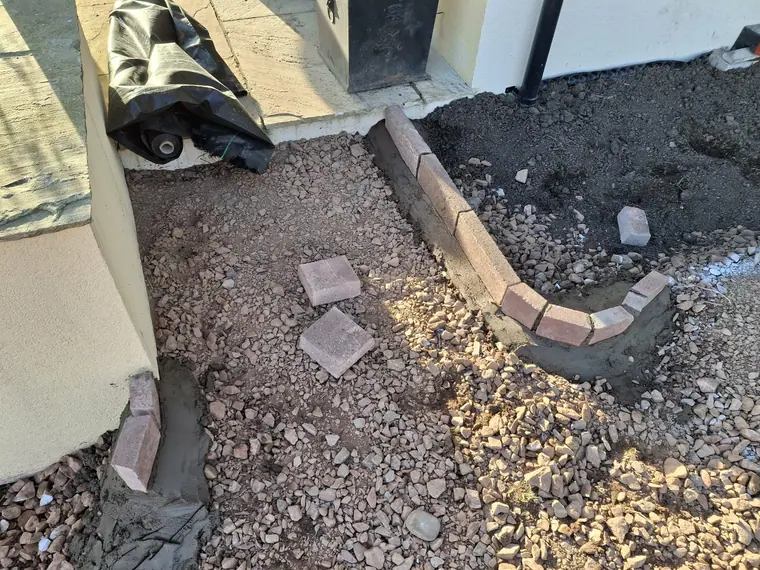 Block edging set on haunching with a gravel drainage margin against the wall.