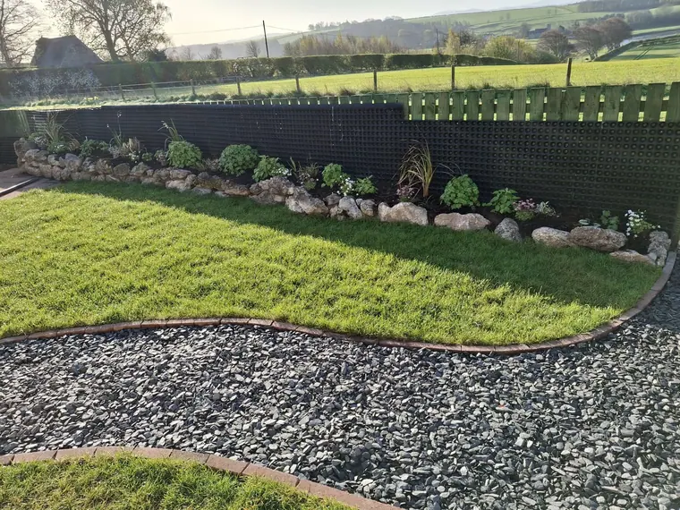 Boulder edging picked from local stone, set into a planted border along the field boundary.
