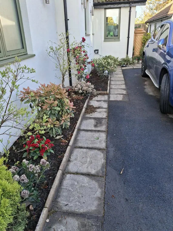 A slab path and planted border built alongside a tarmac drive, keeping cars and feet apart.