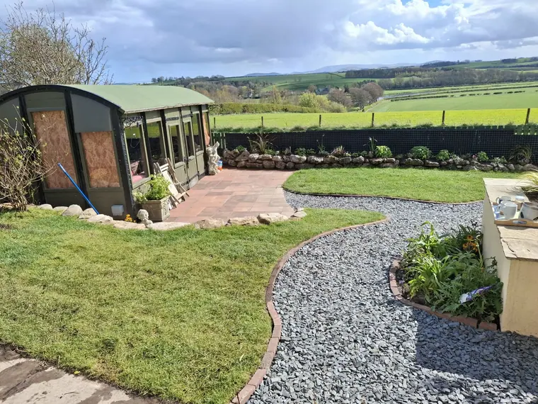 The finished garden looking out over the Tweed valley: curved gravel path, clean lawn, planted borders.