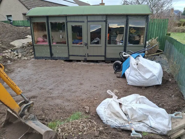 Bare, compacted ground around a tired sun room before landscaping work started