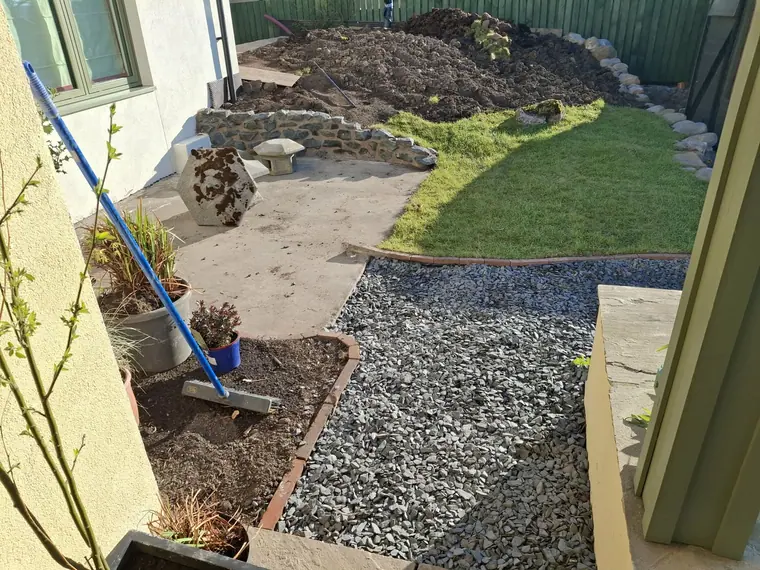 Gravel going in against a fresh edging line, with the first turf already laid behind.