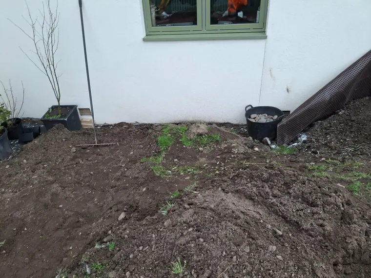 Ground reduced and cleared along the house wall before the new bed and edging go in.