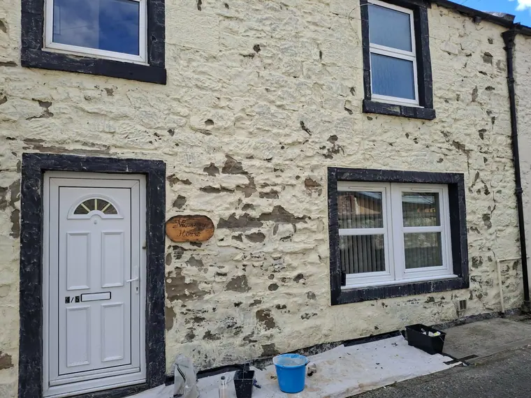 Blown and flaking harl on a village cottage — everything loose comes off before a brush is lifted.