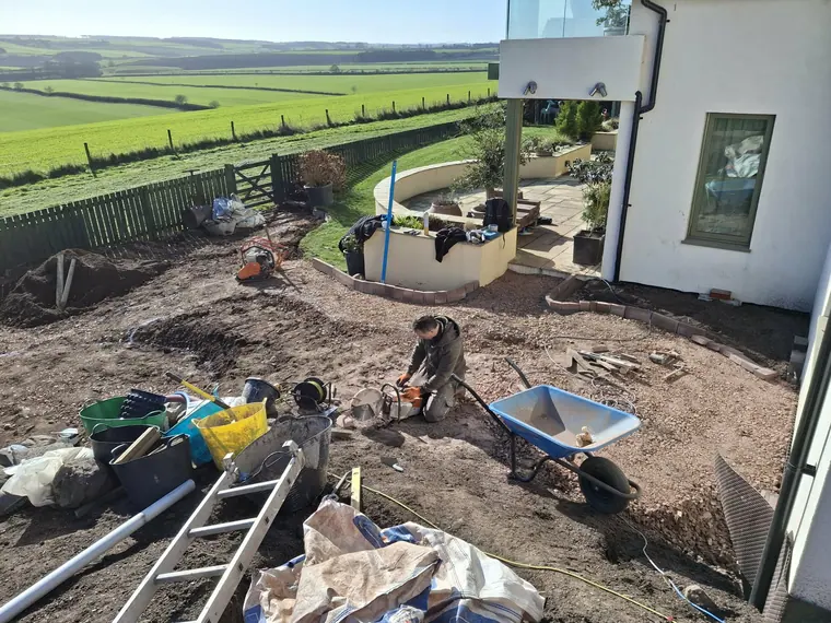 Working the slope above the valley, with the raised terrace and pergola posts already standing.