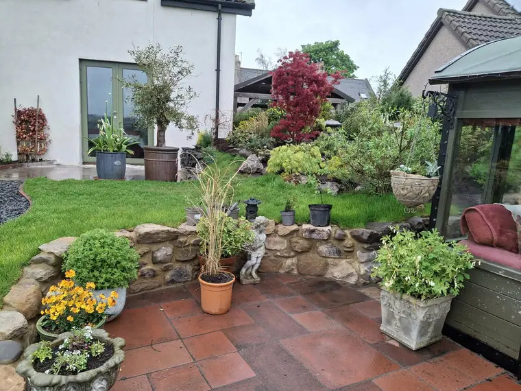 Terracotta paving with a dry stone retaining bed above, planted up and settled in.