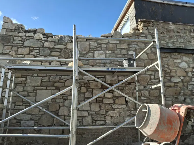 Rebuilding the top courses to the original line, stone by stone, using material salvaged from the wall.