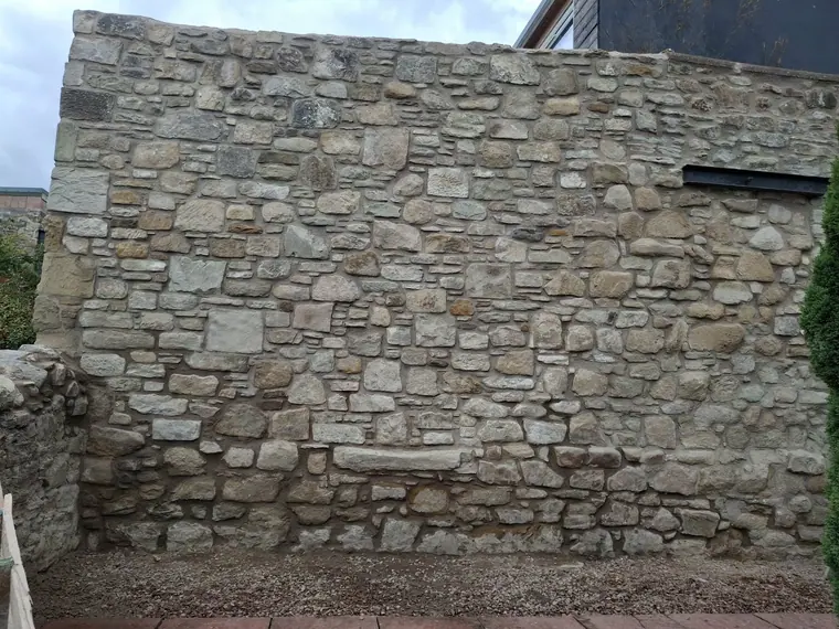 A traditional Borders rubble stone wall after full repointing, with recessed joints and the stone left proud