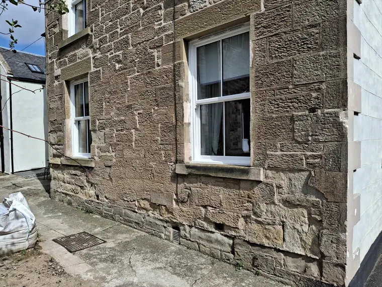A sandstone elevation with quoins and window surrounds made good, ready for the next twenty winters.
