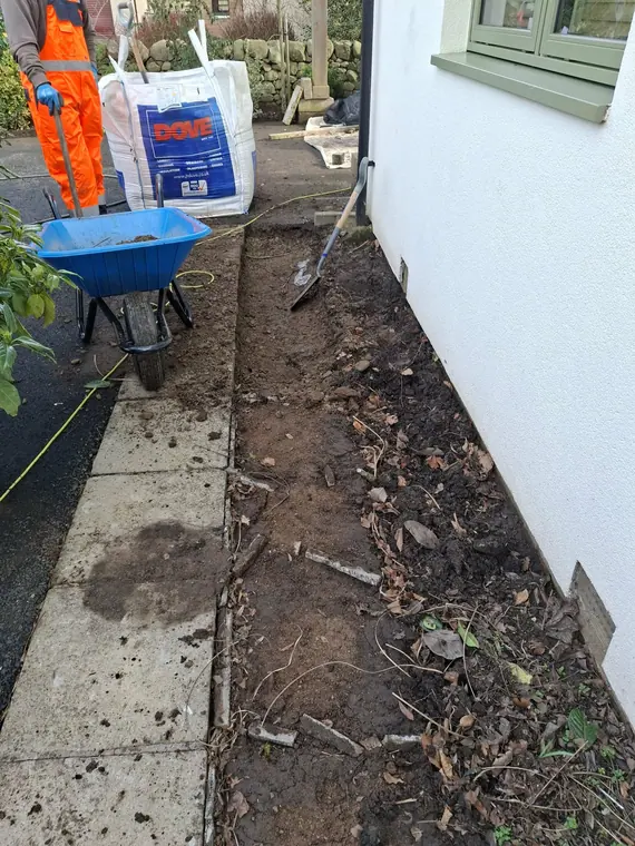 Digging out along the gable for a new path, working in the width available without touching the render.