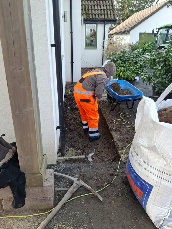 Digging out at the base of a dressed stone corner so the ground level sits below the damp course again.
