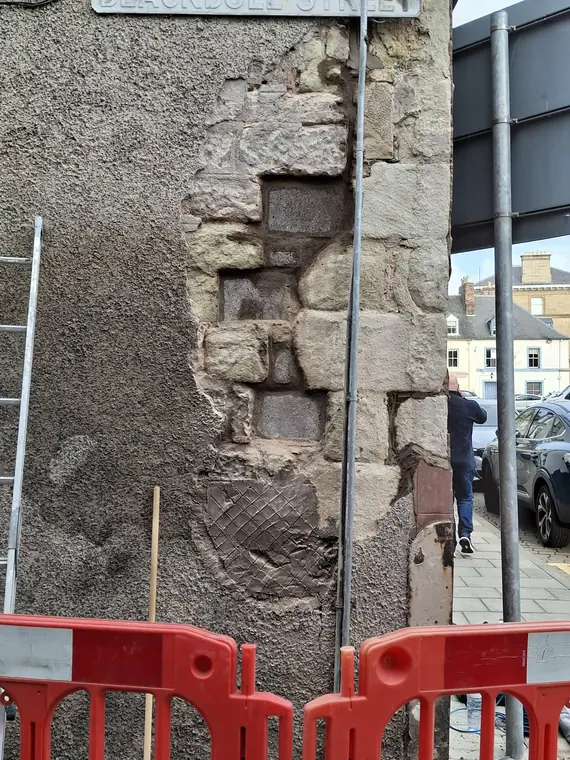 Cutting out the perished stone square and true, ready for new blocks to be indented into the corner.