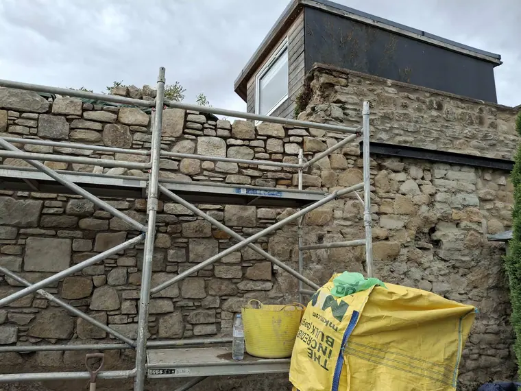 Scaffold up and joints raked out by hand, ready for fresh pointing across the full elevation.