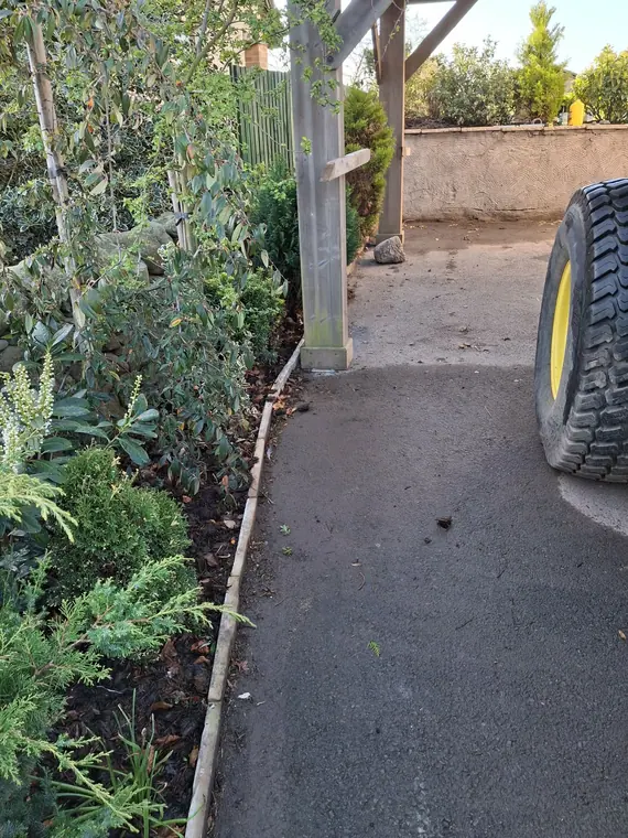 New tarmac laid against a fresh kerb line, with a working machine on it the same week.